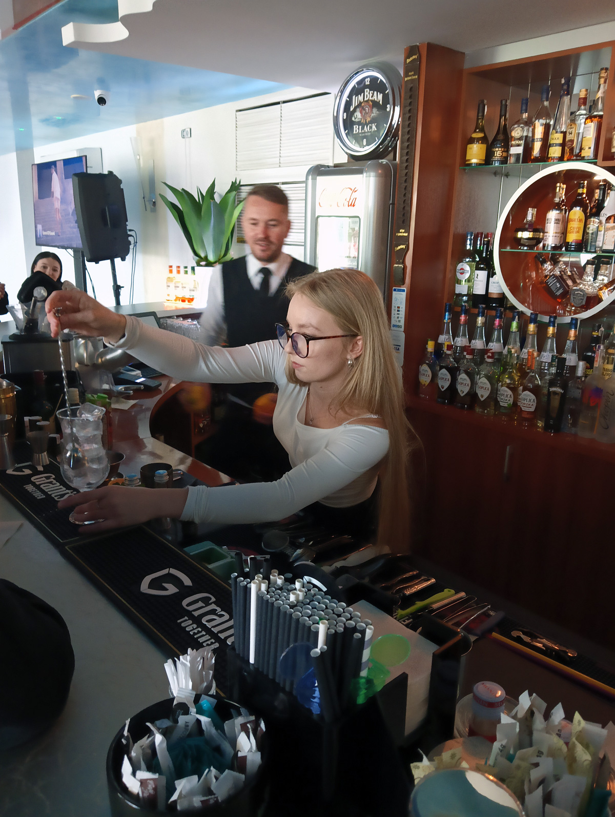 uczennica ze sporządzonym napojem w tle barman