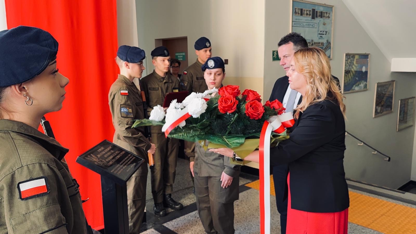 apel szkola pani dyrektro wraz z uczniami w mundurach skladanie kwiatow