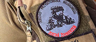 Na zdjęciu widoczny jest emblemat Oddziału Przygotowania Wojskowego (OPW). Symbol przedstawia oznaczenie związane z wojskowym profilem kształcenia uczniów.